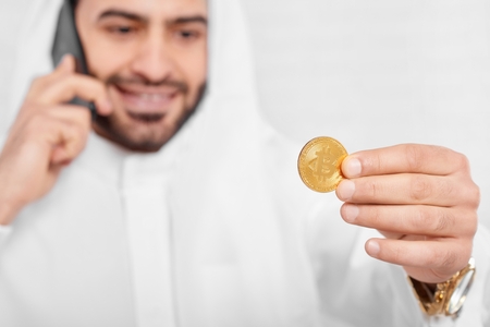 A Muslim businessman looks on golden bitcoin.の写真素材