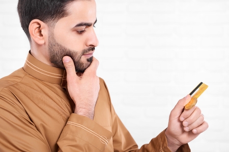 Arabian man keeps golden credit card in his hands.の写真素材