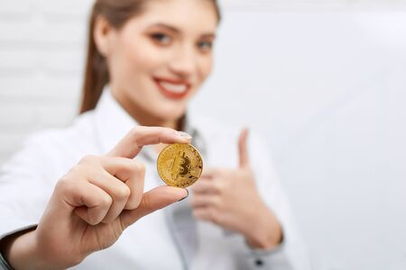 Portrait of a businesswoman wearing dress-code holds golden bitcoin.の写真素材