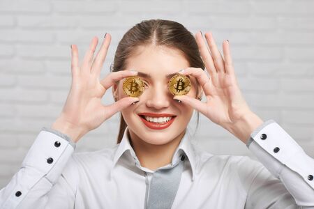 Smiling girl holds two golden bitcoins on the white background.の写真素材