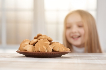 Plate with delicious cookies with little girl on background.の写真素材