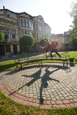 Ivano-Frankivsk, Ukraine - 1 June 2015 : Beatiful yound couple is dancing on citys bench near green plants and original buildings facade. Boy and girl looking happy, satisfied and emotional.のeditorial素材