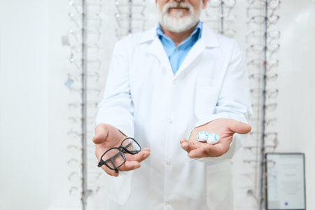 Oculist advising to try the eyeglasses on. expirienced, skilled oculist. Kind professinal helping patients improving vision, be healthy.の写真素材