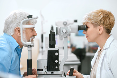 Oculist cheking patients vision with medical equipment, working in ophthalmilogical laboratory....