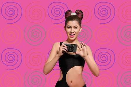 Fancy girl is posing wearing original swimwear is keeping old-fashioned camera . Standing on pink...