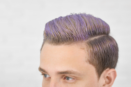Cropped photo of young boy with toned lilac hair looking forward. Having perfect hairdress, modern, stylish, fashionable. Male model having big blue eyes, straight nose, small ears. White background.の写真素材
