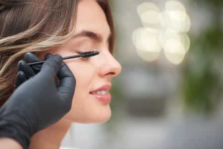 Closeup of process of doing professional makeup to beautiful female client in beauty salon. hands of...