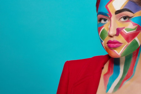 Stylish woman looking at camera, posing. Confident and charming model has creative, colorful pop art make up, pink plump lips. Studio with blue background.の写真素材