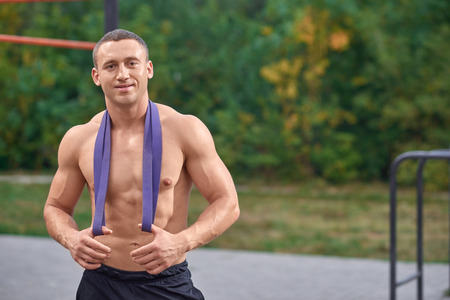 Portrait of handsome, attractive bodybuilder posing, looking at camera and smiling. Sexy and...