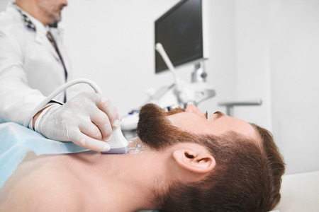 Side view of bearded man face lying on examination in medical cabinet. Doctor wearing in medical...