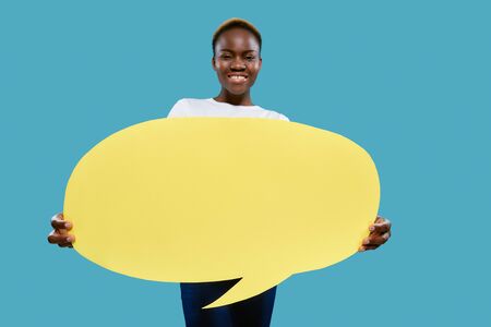 Yellow paper speech bubble with copy space for text in hands of cheerful, positive african woman....