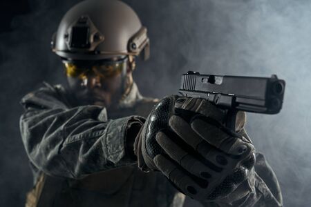 Selective focus of modern little gun in hands of American solider. Angry ranker in helmet and...