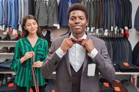 Client choosing suit, dressing white shirt, waistcoat and jacket, looking at camera and smiling....