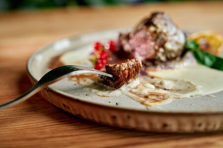 Delicious and tender roast duck with sauce served on plate with fork in restaurant.の写真素材