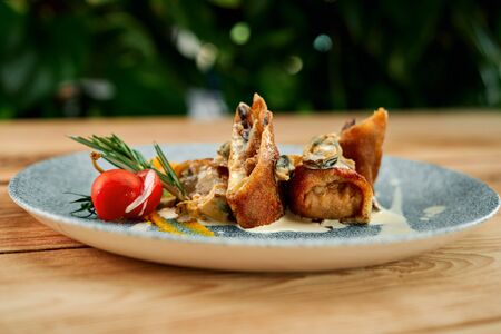 Tasty pancakes with cheese and mushrooms, served on blue plate with white sauce and tomato.の写真素材