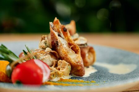 Tasty pancakes with mushrooms and cheese, served on blue plate with white sauce and tomato.の写真素材