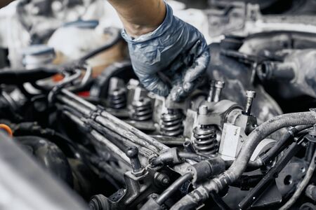 Close up of nozzles in car diesel engine with mechanics hand in blue dirty rubber gloves doing professional auto repairing. Engine maintenance conceptの写真素材