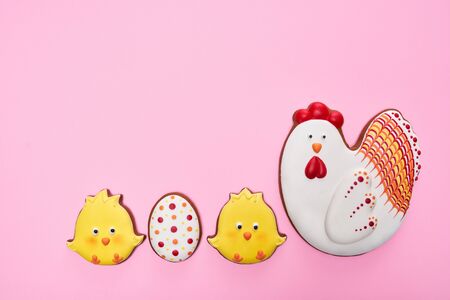 From above view of glazed cookies in shape of lovely chicken, two yellow chicks and egg, isolated on pink background. Close up of cute pastry in row. Spring and easter holidays concept.の写真素材