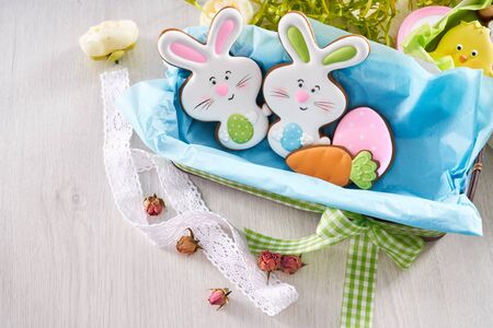 From above view of glazed cookies in shape of lovely bunnies, egg and carrot lying in box with blue...