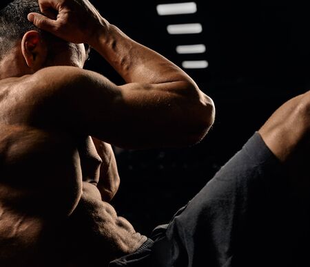 Crop of muscular caucasian man training abs on mat in gym. Side view of incognito sportsman building...