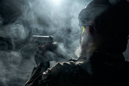 Back view of old military officer holding small gun and aiming. Portrait of bearded veteran in...