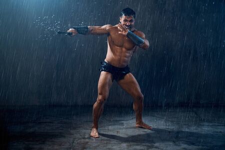 Motion of angry screaming wet roman gladiator swinging sword. Muscular shirtless spartan with...