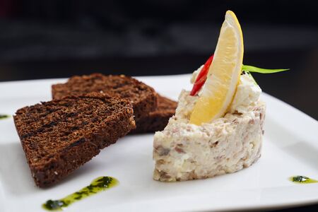 Close up of salad with mayonnaise, dressing and slice of lemon on top. Tasty dish on white plate,...