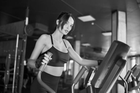 Side view of brunette woman in wireless headphones and sport top doing hard cardio workout on...