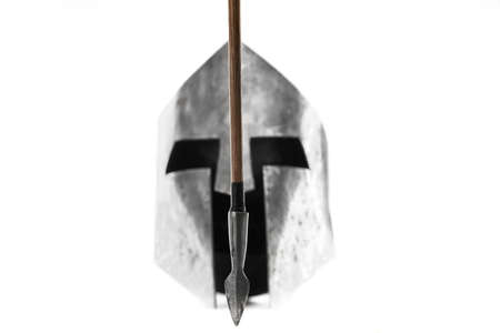 Selective focus of sharp wooden arrow, medieval iron silver helmet on background. Old ancient armour...