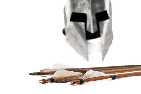 Close up cropped view of ancient metal silver helmet and wooden arrows with grey feathers isolated...