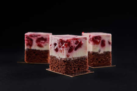 Front view of three delicious fresh pieces of cake made with brown biscuit and mousse pink layer...