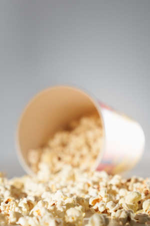 Bowl with spilled popcorn isolated on grey background. Cinema concept.の写真素材