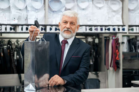 Close up of senior man preparing purchase in store menswear. Concept of boutique with suits.の写真素材