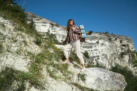 Dark-haired woman with backpack on shoulder walking on rocky mountain at national park Podillya...