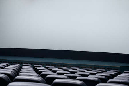 Close up of empty blue cinema hall with white screen. Concept of cinema auditorium.