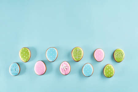 Painted gingerbread eggs covered with colorful glaze isolated over light blue background. Sweets for celebrate Easter.の写真素材
