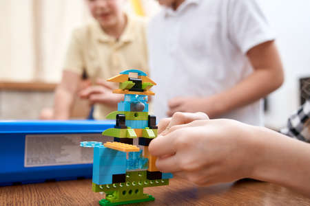Selective focus of hands using building kit for kids, creating toys. Crop of incognito caucasian child working on project, taking colorful parts. Concept of science engineering.の写真素材