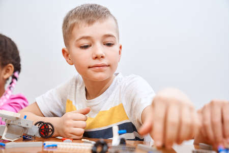 Front view of building kit for group of multiracial kids creating toys, having positive emotions and...