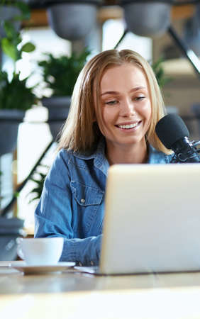 Close up portrait of smiling young attractive woman working in laptop with tasty coffee in cafe....
