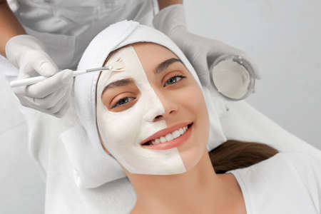 Front view portrait of smiling young brunette woman lying on procedure for face in beautician....