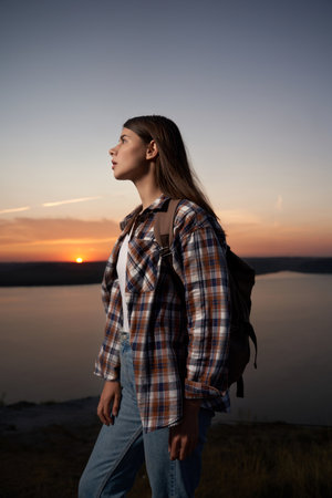 Charming dark-haired woman in checkered shirt walking with backpack at Bakota bay during amazing...