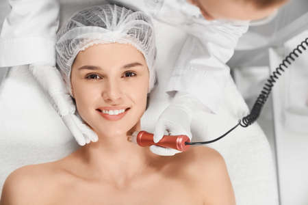 Top view portrait of smiling attractive woman in beautician on procedure for face with special...