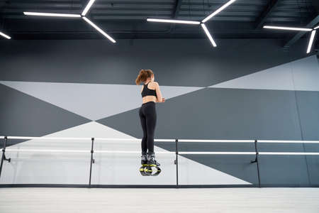 Unrecognizable caucasian girl wearing black clothes practicing jumps. From below back view of...