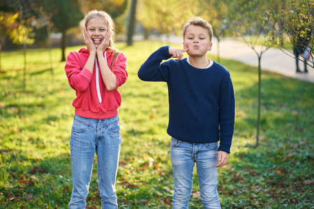 Brother and sister smiling and posing on sunny day in park. Concept of family weekend.の写真素材