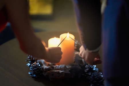Close up of man and woman using candles for lighting sparklers. Young stylish couple celebrating christmas or new year at home. Festive mood concept.の写真素材