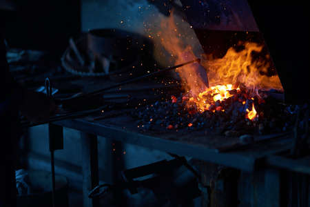 Piece of metal heating under high temperature inside fireplace at forge. Preparation of material for...