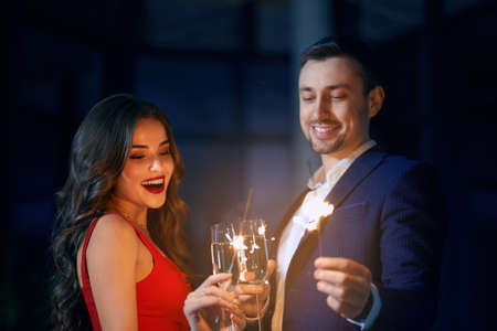 Front view of happy beautiful young woman in red dress and handsome young man in elegant suit...