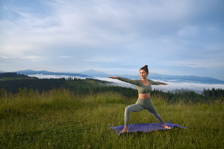 Active female person in sport outfit doing yoga exercises outdoors. Young woman spending summer day on fresh air for intense workout.の写真素材