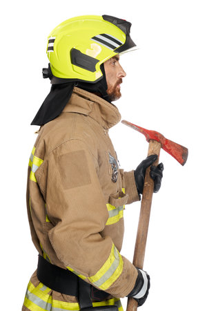 Focused male fireman using wooden axe tool for work. Side view of middle-aged man in fire uniform with hatchet looking away, isolated on white studio background. Job, equipment, tool concept.の写真素材