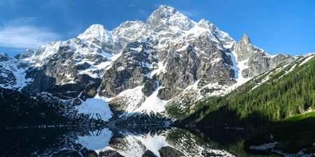 Panoramic view of rocky mountains and mountain lake with reflections of mountains on itの写真素材